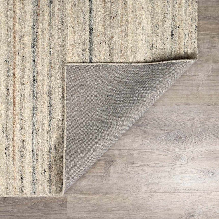 Close-up of the hand-tufted Capote Ivory Area Rug showing its wool texture and charcoal, tan, and taupe vertical stripes. Fold