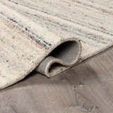 Close-up of the hand-tufted Capote Ivory Area Rug showing wool texture and charcoal, tan, and taupe color variations. Fold