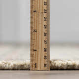 Close-up of the Capote Ivory Area Rug showing its pile height of approximately 1 inch with a ruler. Pile