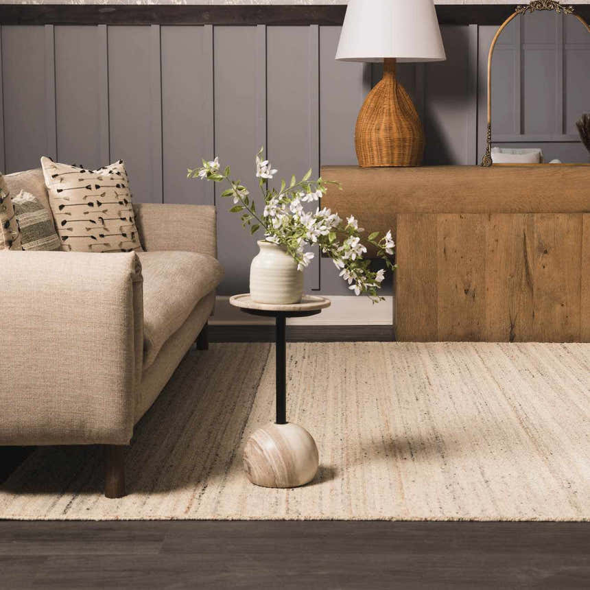 Living room scene with a Capote Ivory Area Rug, beige sofa, side table with flowers, and wood console. Roomscene-Rectangle