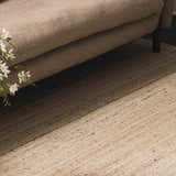 Close-up of the Capote Ivory Area Rug showing its textured wool design, ivory and charcoal colors, and subtle linear pattern. Roomscene-Rectangle