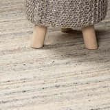 Close-up of the hand-tufted Capote Ivory Area Rug showing its charcoal, tan, and ivory hues and textured wool fibers. Styleshot