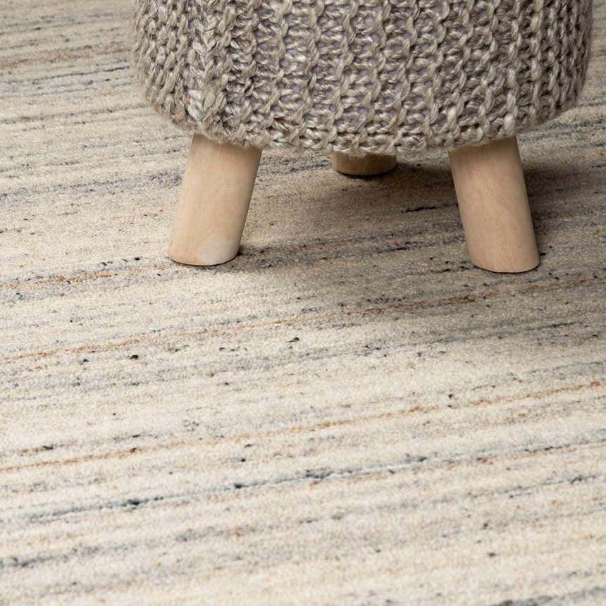 Close-up of the hand-tufted Capote Ivory Area Rug showing its charcoal, tan, and ivory hues and textured wool fibers. Styleshot