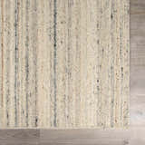 Close-up of the Capote Ivory Area Rug. Hand-tufted wool rug with charcoal, tan, and taupe vertical stripes. Swatch