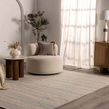 Living room scene with a Capote Charcoal Area Rug, ivory chair, and wood accents. Roomscene-Rectangle