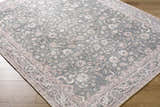 Close-up of the Anando Washable Area Rug. Features a traditional floral pattern in cream, light green, orange, and pale pink. Corner