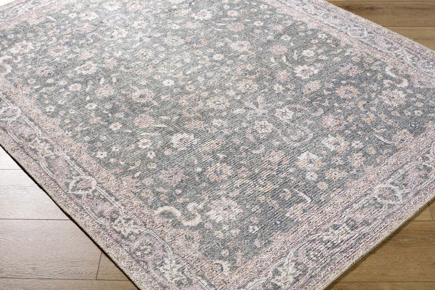 Close-up of the Anando Washable Area Rug. Features a traditional floral pattern in cream, light green, orange, and pale pink. Corner