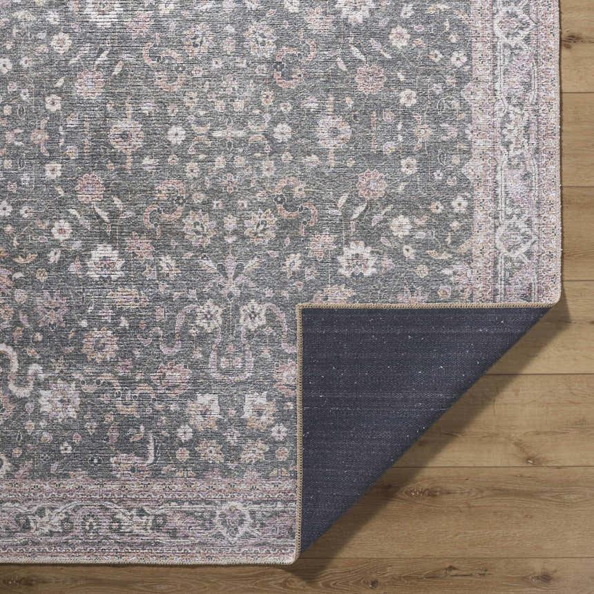 Close-up of the Anando Washable Area Rug showing a traditional floral pattern in cream, green, orange, and pale pink. Fold