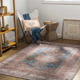 Living room scene with Baltinglass Rust & Blue Washable Area Rug, white chair, and wooden side table. Farmhouse style. Roomscene-Rectangle