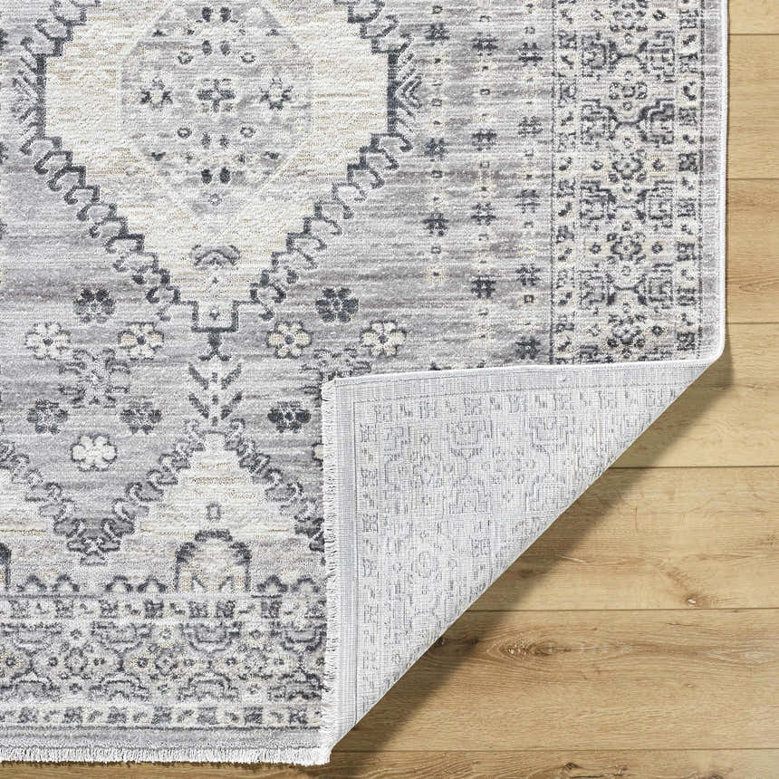 Close-up of the Aoibhe Area Rug. Ivory, medium gray, and slate gray traditional pattern. Machine woven polyester rug. Fold