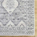 Close-up of the Aoibhe Area Rug. Ivory, medium gray, and slate gray traditional floral pattern. Corner