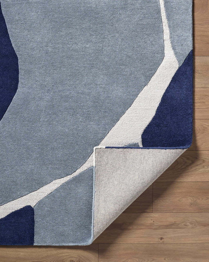 Close-up of the hand-tufted Robbins Modern Blue Wool Rug, featuring a geometric pattern in blue, light slate, and navy. Fold