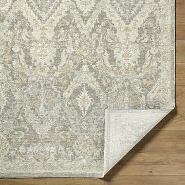Close-up of the Almaas Medium Gray rug showing its traditional pattern, luxe texture, and folded corner on wood floor. Fold