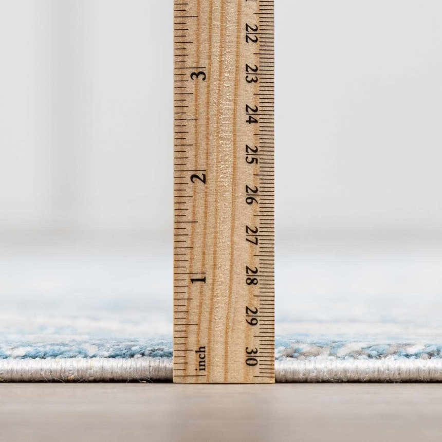 Close-up of the Rydalmere Rug pile height, showing its soft texture and light blue pattern with a ruler for scale. Pile