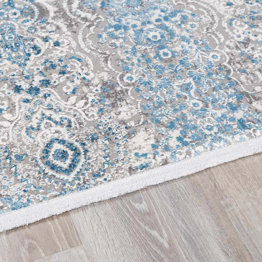 Close-up of the Rydalmere Luxury Ultra Soft Rug. Features a traditional blue and gray floral pattern on a light wood floor. Pile