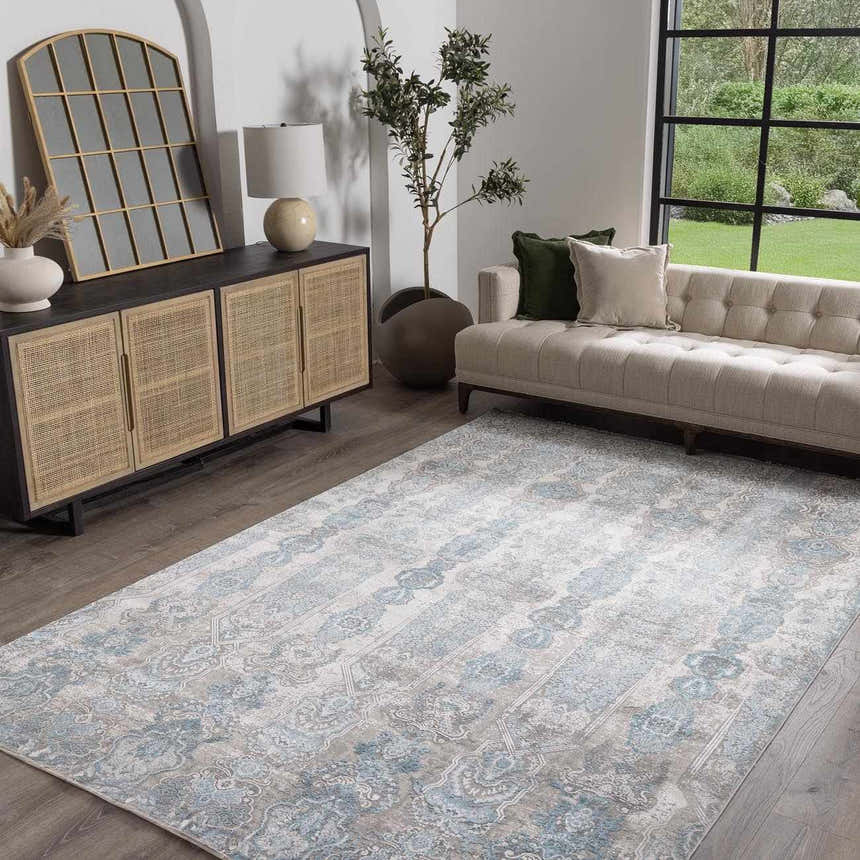 Living room scene with a Rydalmere Luxury Ultra Soft Rug in gray and blue tones, complementing the neutral sofa and wood furniture. Roomscene-Rectangle