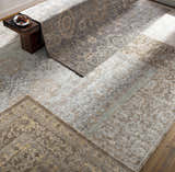 Stock Area Rug - Clearance in a room scene. Charcoal, beige, and sage rugs layered on the floor with a wood bench. Styleshot