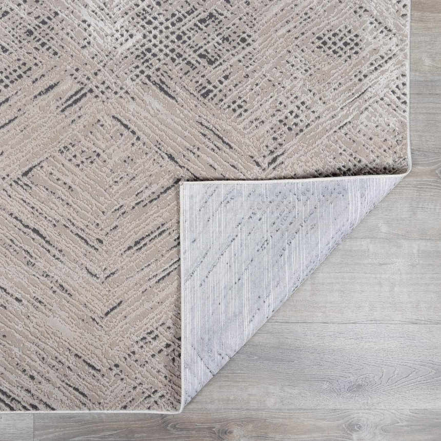Close-up of the Garza Diamond Textured Washable Rug in beige and gray, showing the diamond pattern and textured weave. Fold