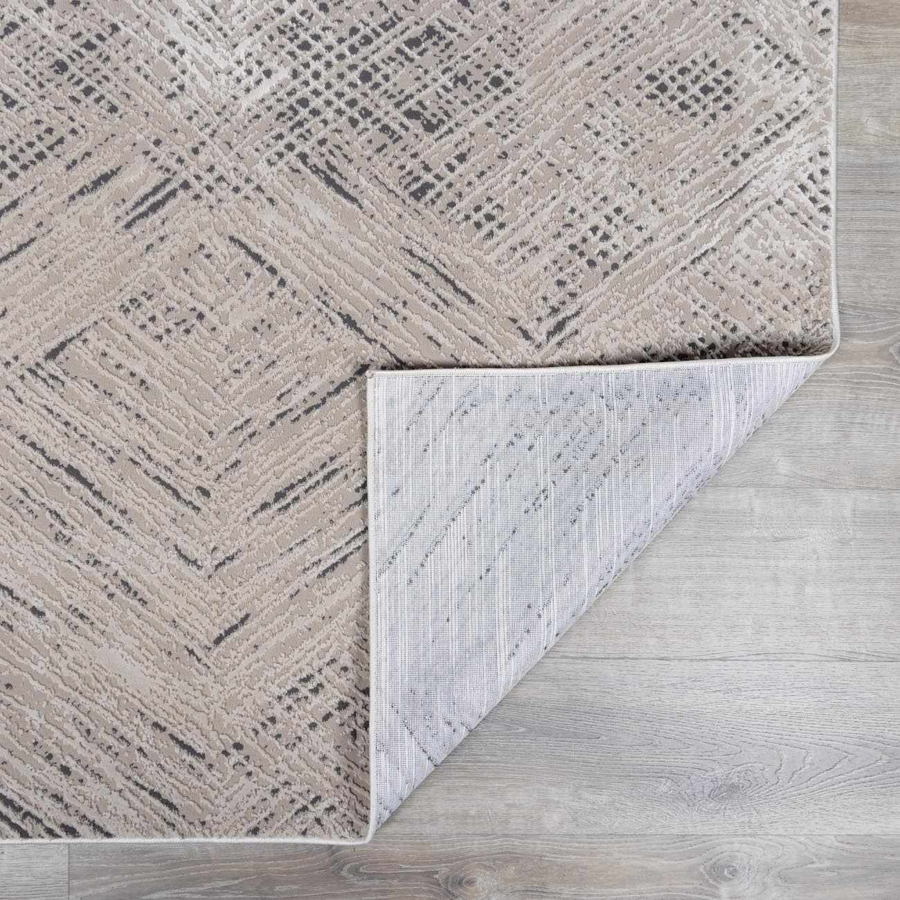 Close-up of the Garza Diamond Textured Washable Rug in beige and gray, showing the diamond pattern and textured weave. Fold