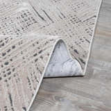 Close-up of the Garza Diamond Textured Washable Rug. Beige and gray tones with a modern, abstract pattern. Folded edge detail. Fold