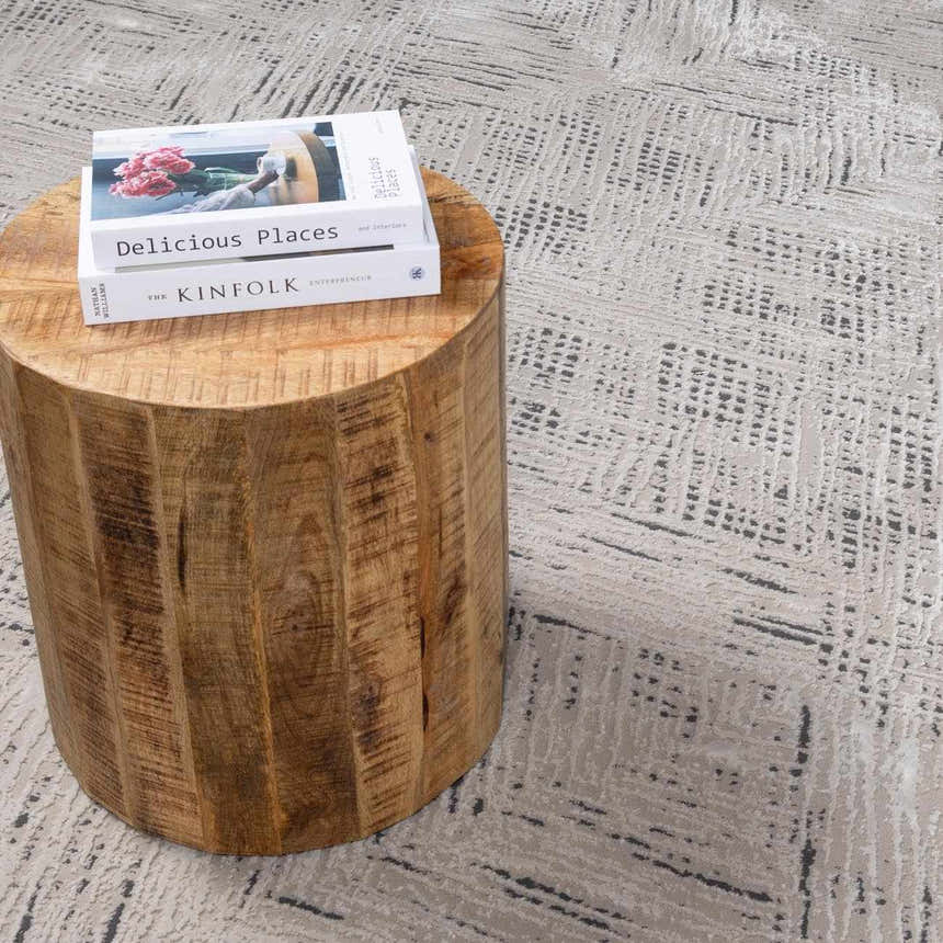 Close-up of the beige Garza Diamond Textured Washable Rug with a contemporary pattern and a wooden side table. Styleshot