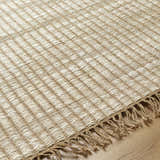 Close-up of the beige Mihal Area Rug showing its jute texture, hand woven construction, and fringe detail. Texture