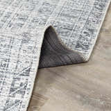 Close-up of the Barny Gray Blue Washable Rug showing its charcoal and off-white distressed pattern and gray backing. Fold