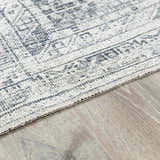 Close-up of the Barny Gray Blue Washable Rug, showcasing its traditional pattern and soft texture on a wood floor. Pile