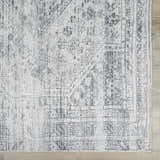 Close-up of the Barny Gray Blue Washable Rug, showcasing its traditional pattern, gray and off-white tones, and soft chenille texture. Swatch