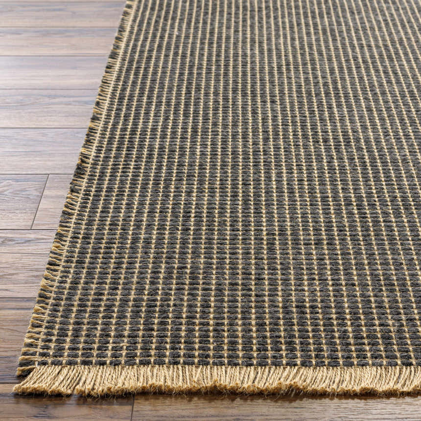 Close-up of Kimi Machine Woven Becki Owens x LIVABLISS rug showing black and light brown grid pattern and jute texture. Front
