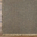 Close-up of Kimi Becki Owens x LIVABLISS BOKM-2305 Area Rug. Black and light brown jute rug with woven grid pattern and fringe. Corner