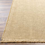 Close-up of the light brown Kimi Machine Woven Becki Owens x LIVABLISS area rug showing jute texture and fringe detail. Front