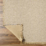 Close-up of Kimi Machine Woven Becki Owens x LIVABLISS rug showing jute texture, gray, tan, and light brown colors. Fold