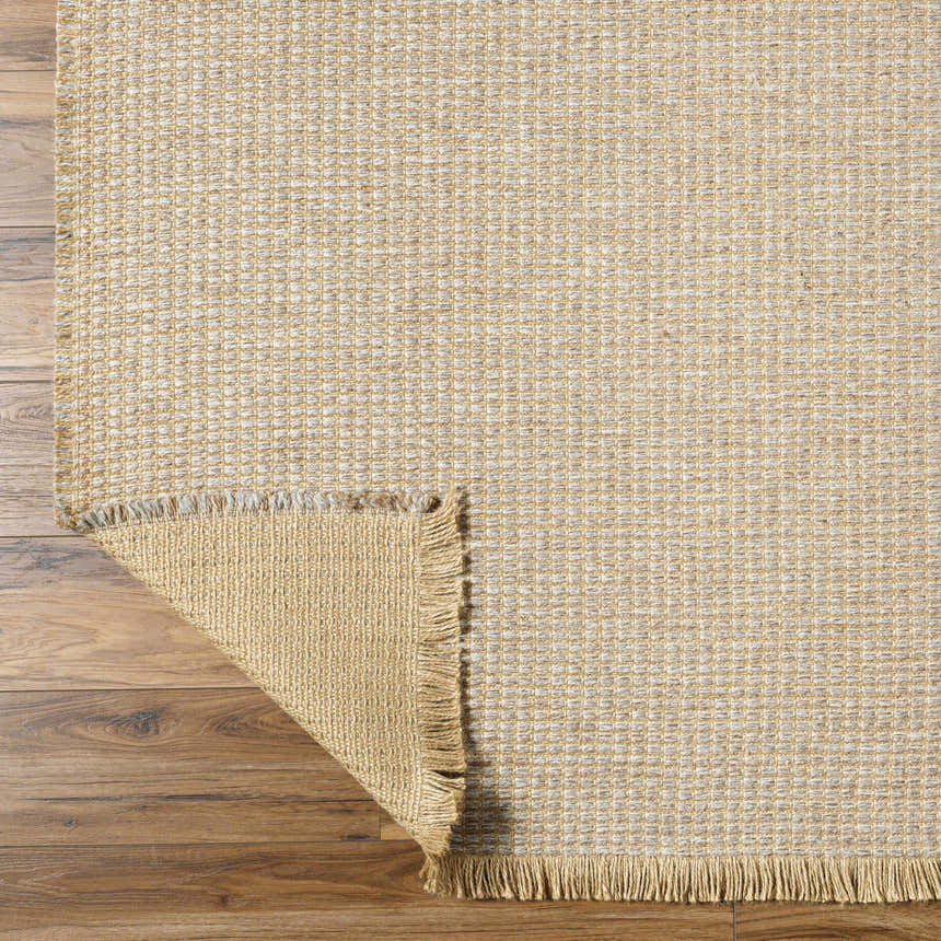 Close-up of Kimi Machine Woven Becki Owens x LIVABLISS rug showing jute texture, gray, tan, and light brown colors. Fold