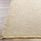 Close-up of the Kimi Machine Woven Becki Owens x LIVABLISS rug showing gray, tan, and light brown jute texture with fringe. Front