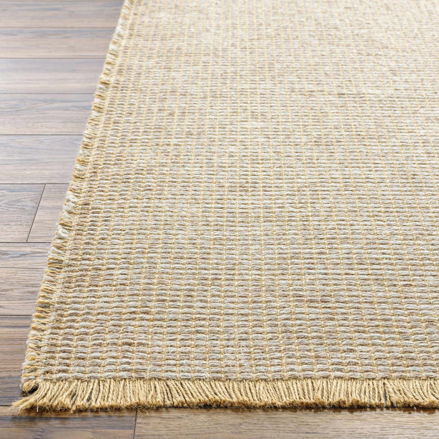 Close-up of the Kimi Machine Woven Becki Owens x LIVABLISS rug showing gray, tan, and light brown jute texture with fringe. Front