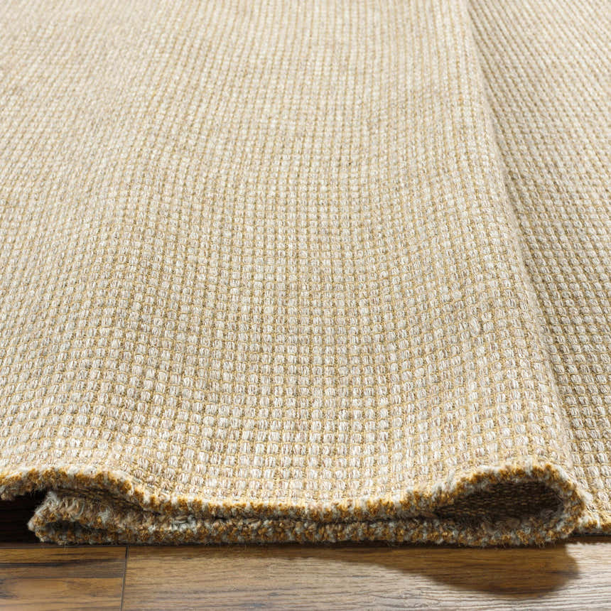 Close-up of the Kimi Machine Woven Becki Owens x LIVABLISS rug showing its jute texture and gray, light brown, and tan colors. Texture