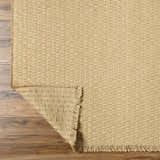 Close-up of the light brown Kimi Machine Woven Becki Owens x LIVABLISS BOKM-2300 area rug showing jute texture and fringe. Fold