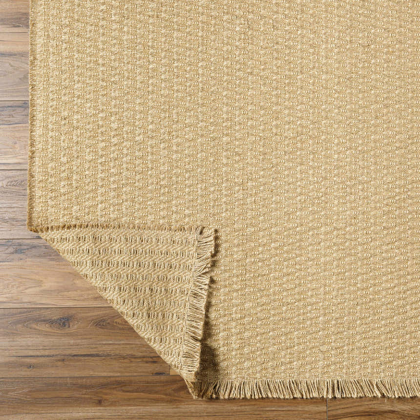 Close-up of the light brown Kimi Machine Woven Becki Owens x LIVABLISS BOKM-2300 area rug showing jute texture and fringe. Fold