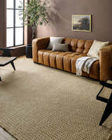 Living room scene with a light brown Kimi Machine Woven Becki Owens x LIVABLISS area rug, leather sofa, and brown walls. Roomscene-Rectangle