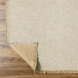 Close-up of Kimi Machine Woven Becki Owens x LIVABLISS rug. Gray and light brown jute texture with fringe detail. Fold