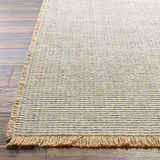 Close-up of Kimi Becki Owens x LIVABLISS rug. Jute texture in gray and light brown with fringe detail on wood floor. Front