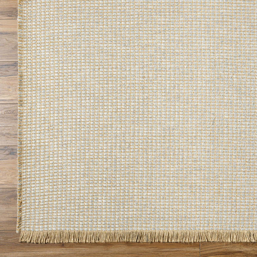 Close-up of Kimi Machine Woven Becki Owens x LIVABLISS rug. Gray and light brown jute texture with fringe detail. Corner