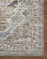 Close-up of the Jyler Traditional Area Rug showing beige, gold, and blue tones with a classic, ornate pattern. Corner