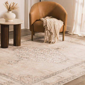 Living room scene with a Lila Medallion Brown Area Rug, tan leather chair, side table with vase, and neutral tones. Roomscene-Rectangle