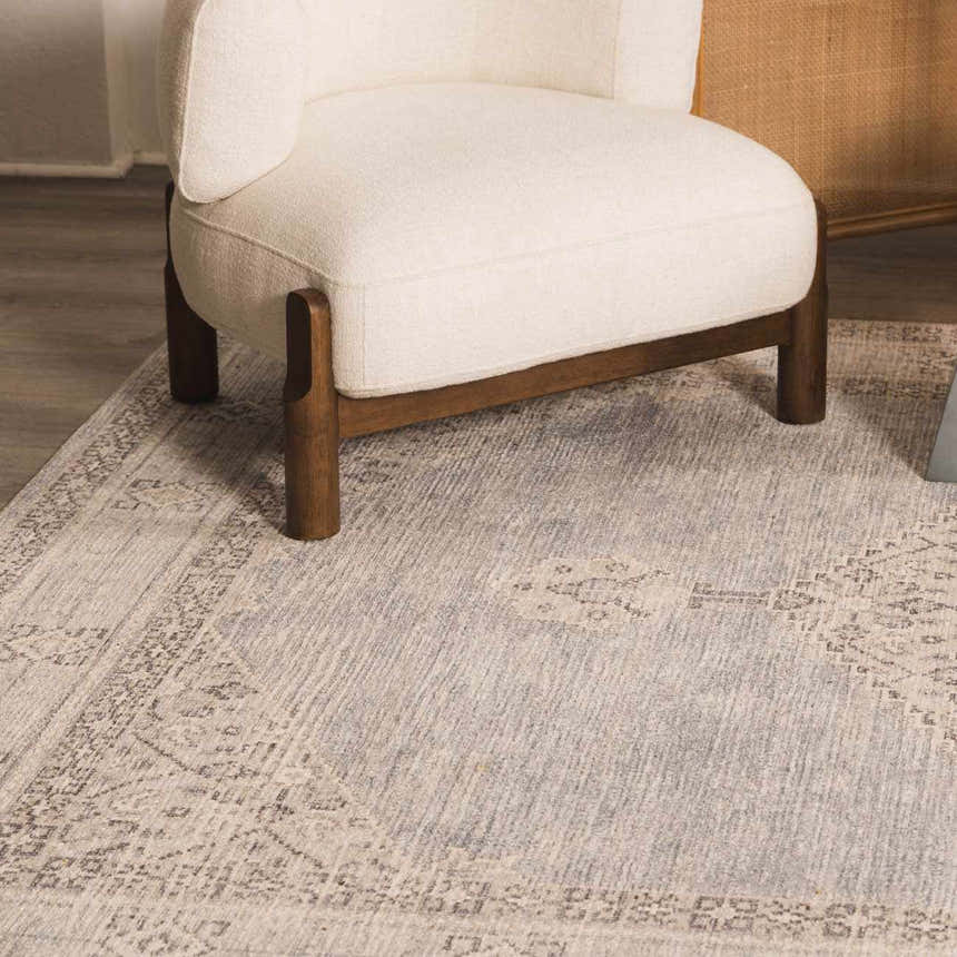 Close-up of the Lila Medallion Denim Area Rug with a traditional gray pattern under a modern white chair. Roomscene-Rectangle