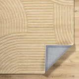 Close-up of the beige Whan Area Rug showing its hand-tufted texture and contemporary linear and curved pattern. Fold
