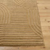 Close-up of the hand-tufted Whan Camel Area Rug showing its geometric pattern and textured wool on wood floor. Front