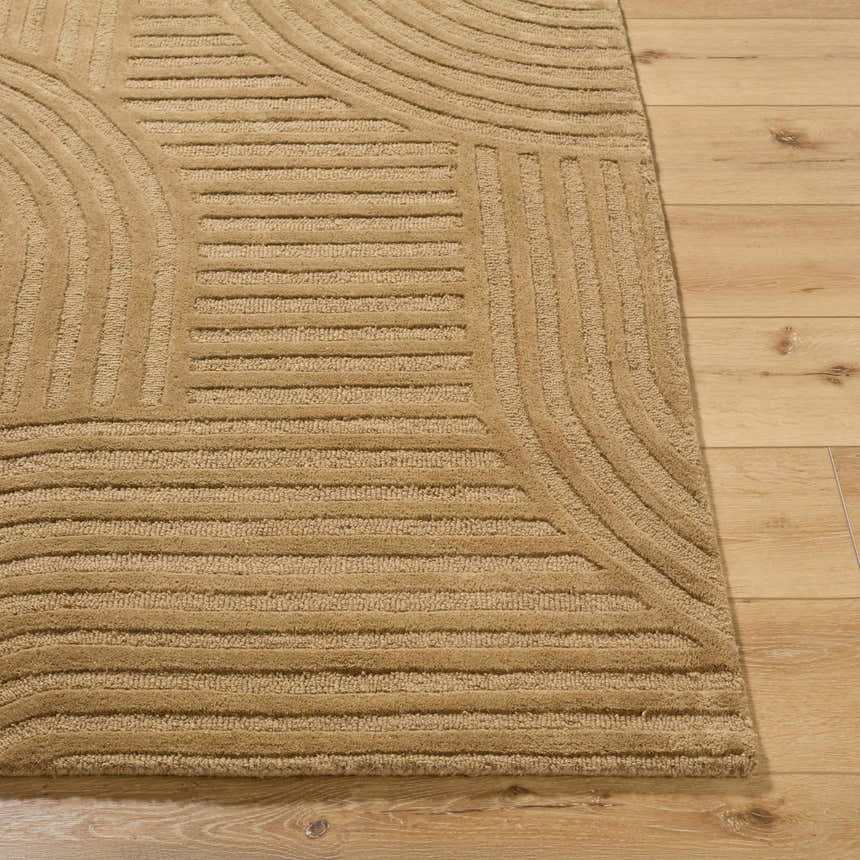Close-up of the hand-tufted Whan Camel Area Rug showing its geometric pattern and textured wool on wood floor. Front