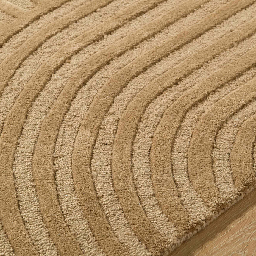 Close-up of the hand-tufted Whan Camel Area Rug. The 100% wool rug features a contemporary, curved line design. Texture